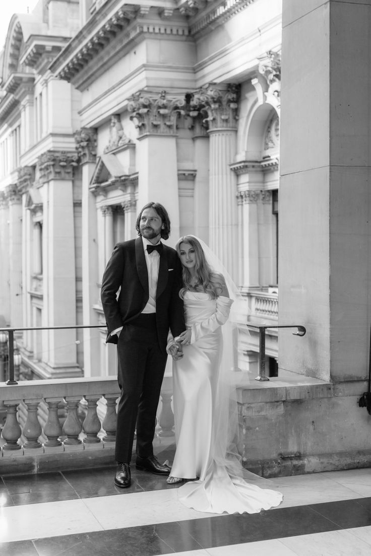 a bride and groom posing for a photo in front of an old building with columns