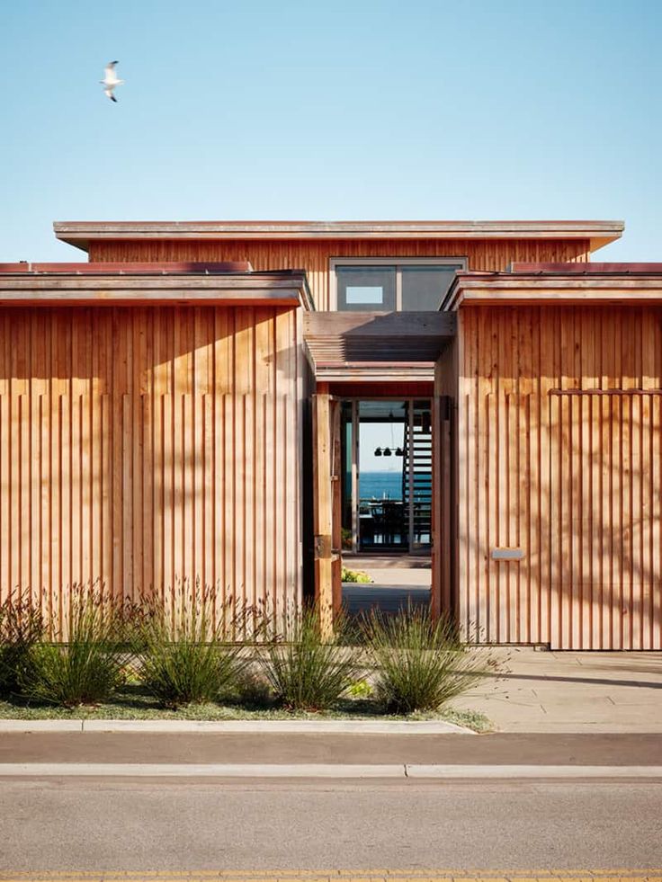 a building with wooden slats on the side and grass growing in front of it