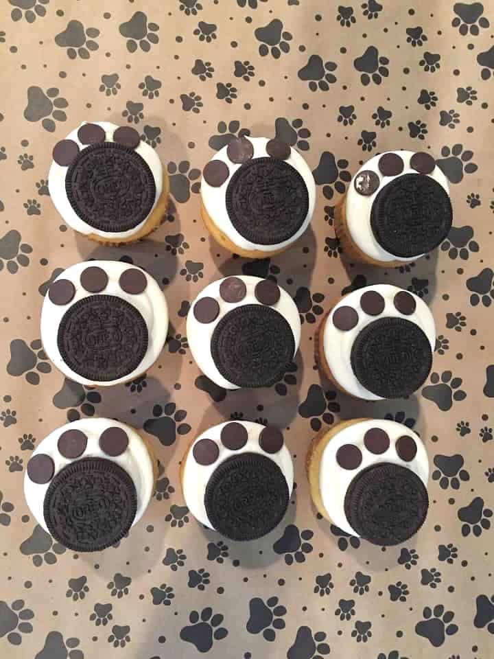 cupcakes with chocolate and white frosting decorated to look like paw prints on a table