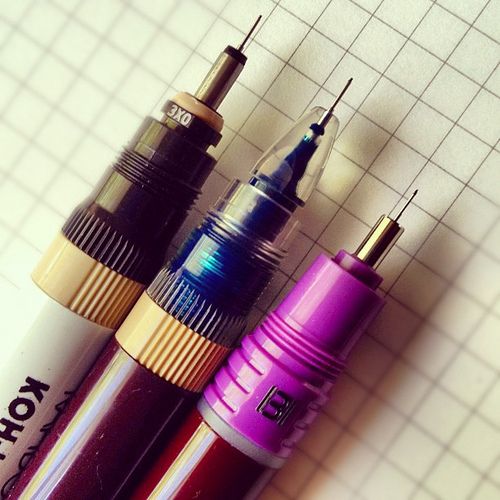 three different colored pens sitting on top of a white tiled floor next to each other