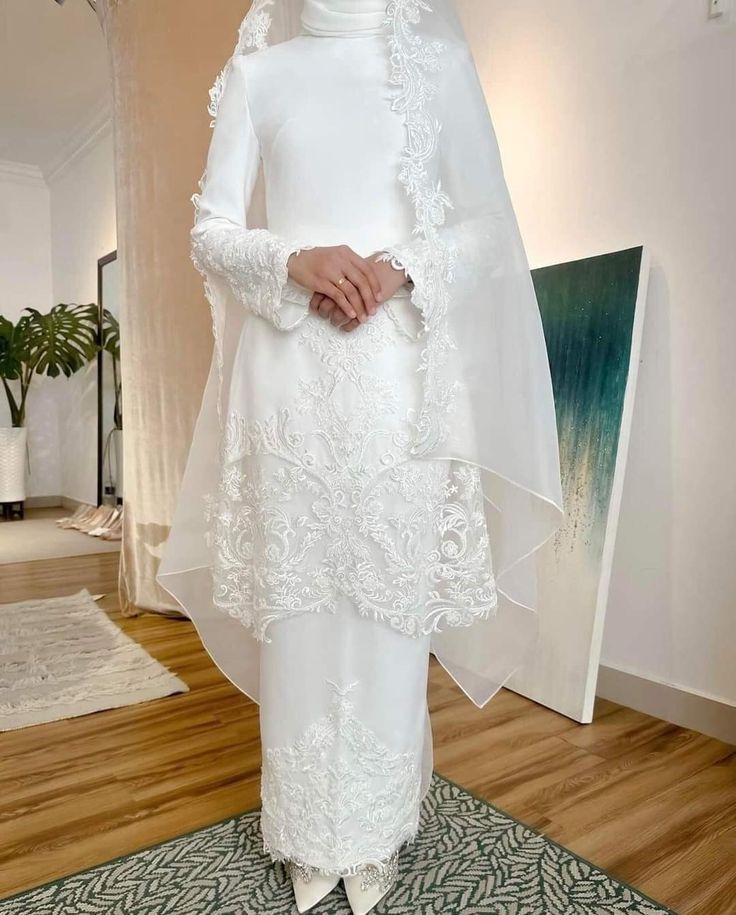 a woman standing in front of a painting wearing a white dress and veil with flowers on it