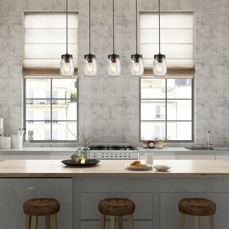 a kitchen island with stools and lights hanging from it's ceiling over the counter