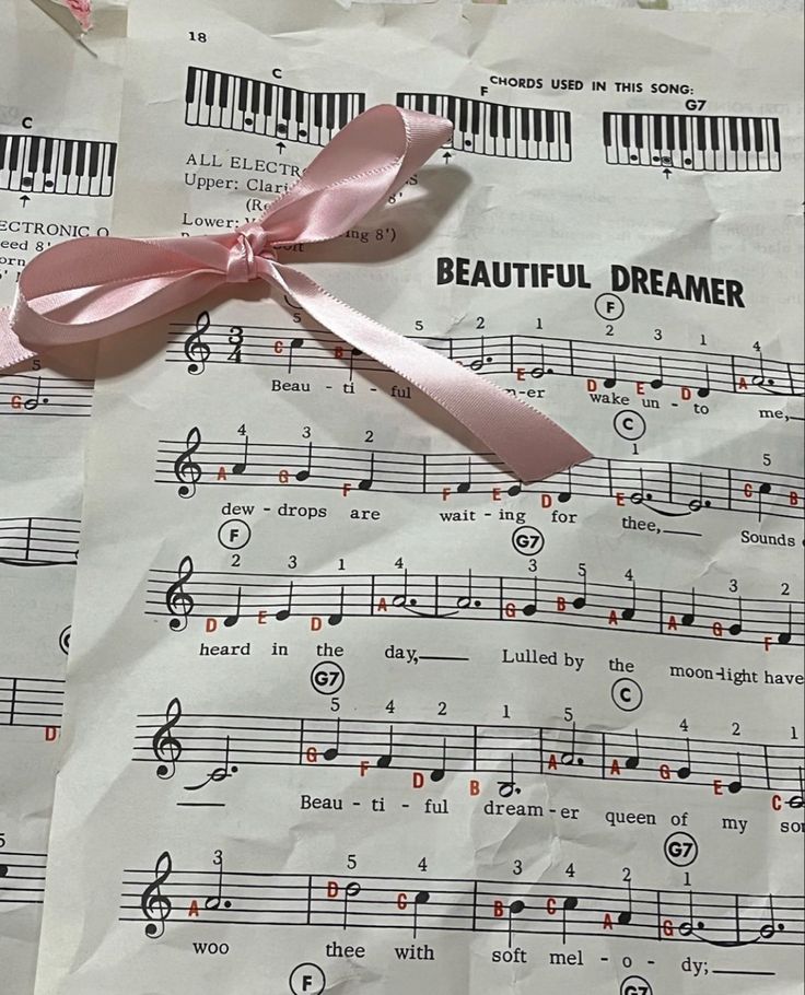 sheet music with pink ribbon laying on top of it's notes and some words