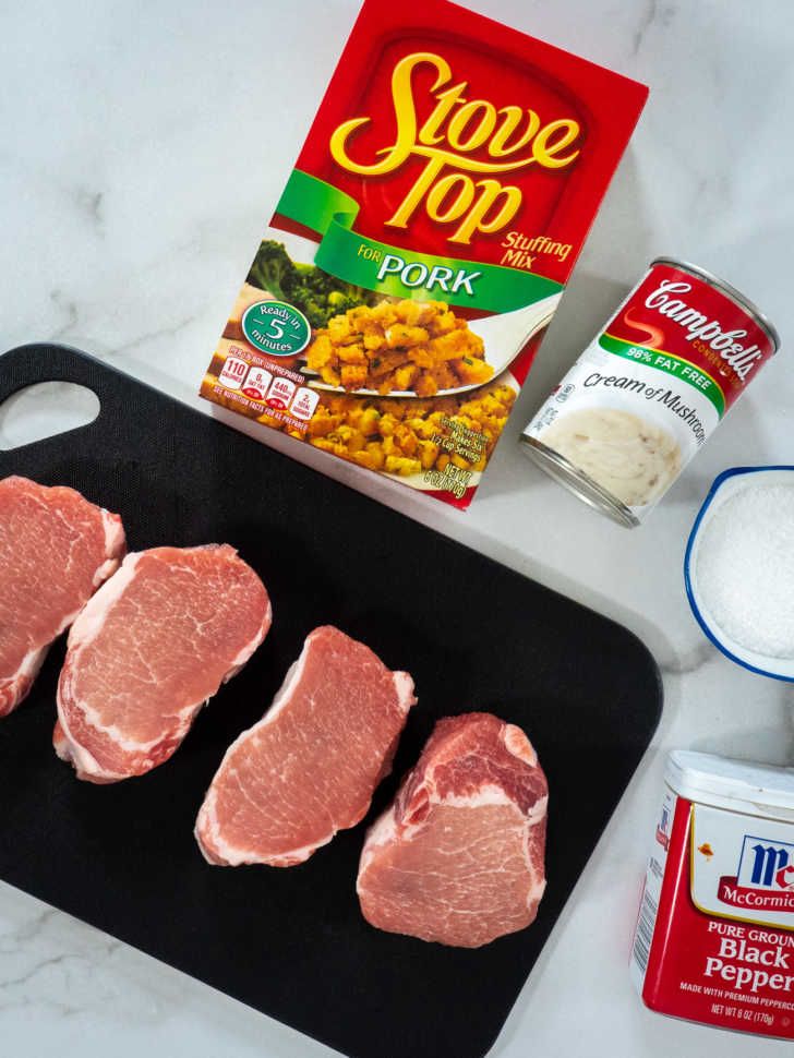 raw pork chops on a baking sheet with spices and seasoning next to them