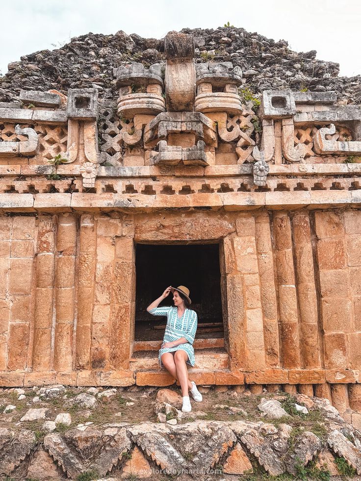 a woman sitting on the ledge of an ancient building with her hand in her hair