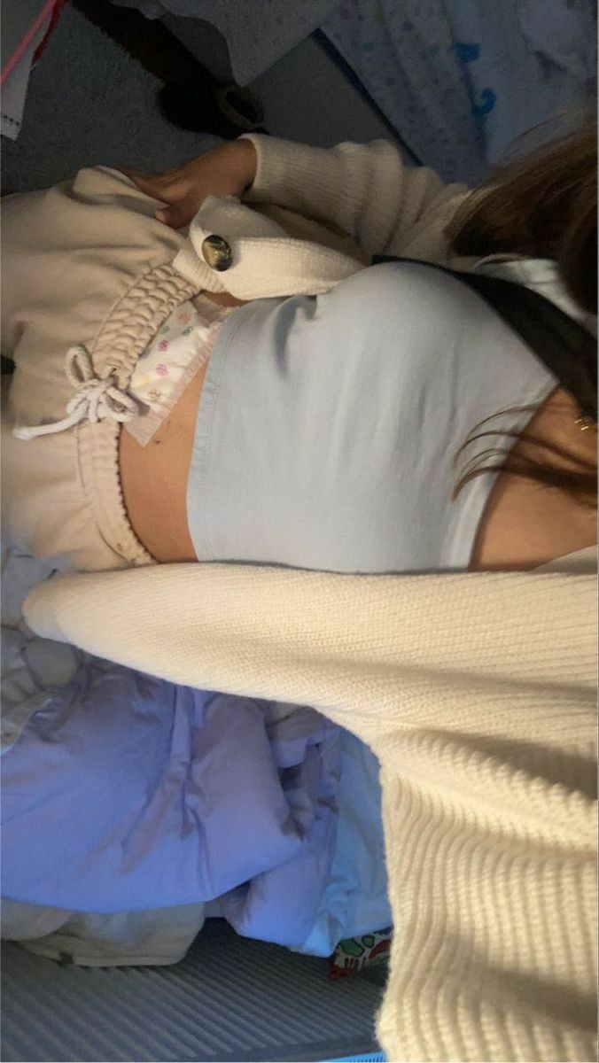 a woman laying on top of a bed covered in white sheets