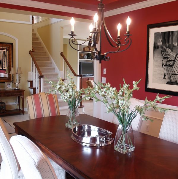 a dining room table with chairs and vases on it in front of the stairs