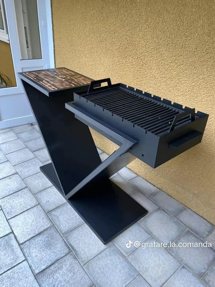 a bbq grill sitting on top of a tiled floor next to a yellow building