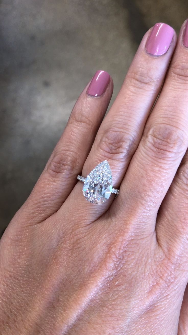 a close up of a person's hand with a diamond ring on her finger