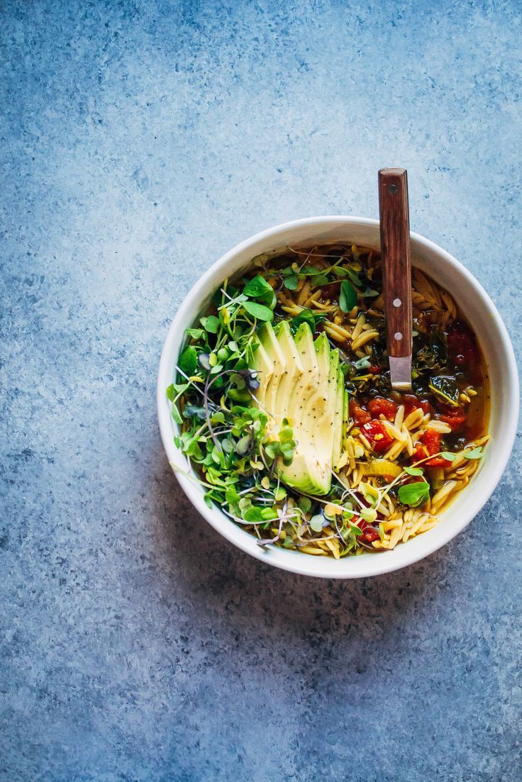 a white bowl filled with soup and an avocado