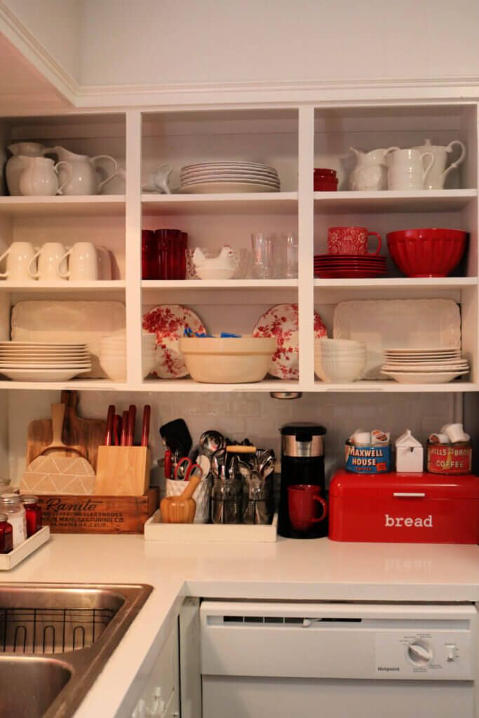 a kitchen with white cupboards filled with dishes