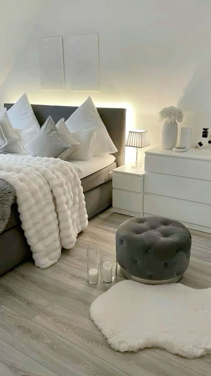 a bedroom with white walls and wood flooring is decorated in shades of grey and white