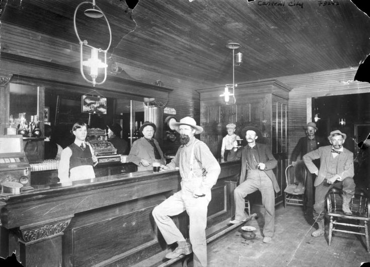 an old black and white photo of men sitting at a bar