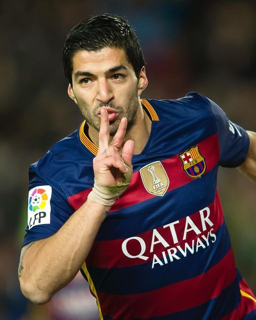 a soccer player is making the peace sign with his hand as he stands in front of him