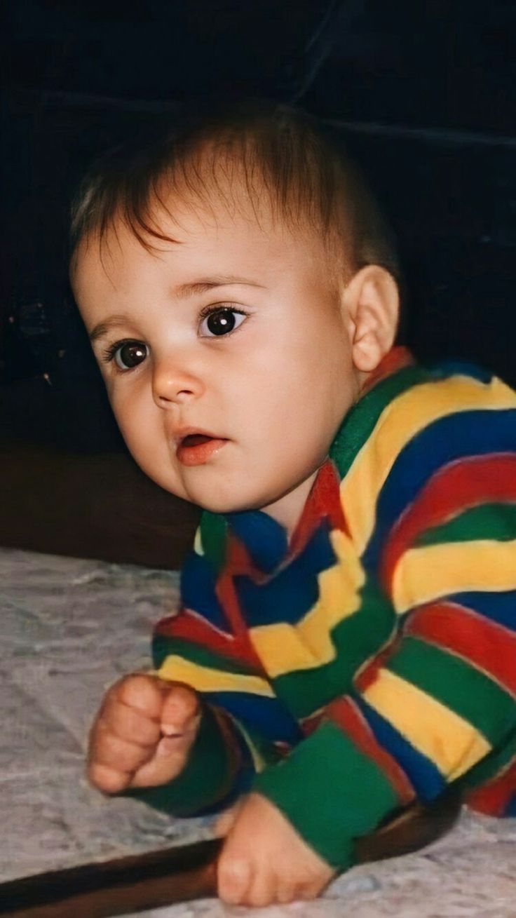 a baby is sitting on the bed looking at something