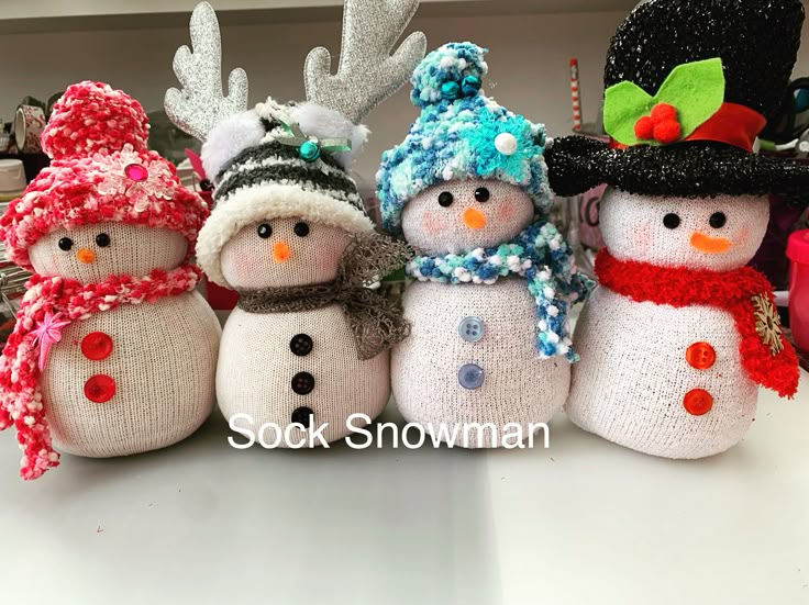 knitted snowmen with hats and scarves are lined up in a row on a table