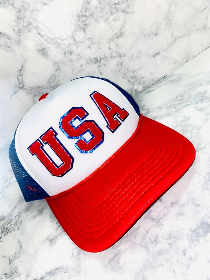 This USA Chenille Trucker Hat is the perfect way to show your patriotic spirit in style! Featuring chenille and a casual good looking trucker hat, it's perfect for sunny days spent outdoors so that you can stay cool and comfortable all summer long. Show your USA pride and look cute every day with this patriotic hat. American Flag Hats For Memorial Day, American Style Hats For 4th Of July, American Style 4th Of July Hat With American Flag, American Flag Hats For 4th Of July, Patriotic American Flag Hat For 4th Of July, Memorial Day Hats Adjustable Made In Usa, Patriotic Hats Made In Usa For Memorial Day, Patriotic White Hat For Summer, Adjustable Hat Made In Usa For Memorial Day