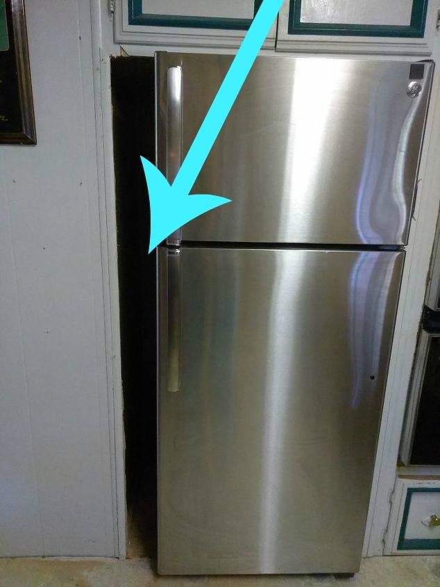 a stainless steel refrigerator in a kitchen next to a white cabinet with green trim on the doors