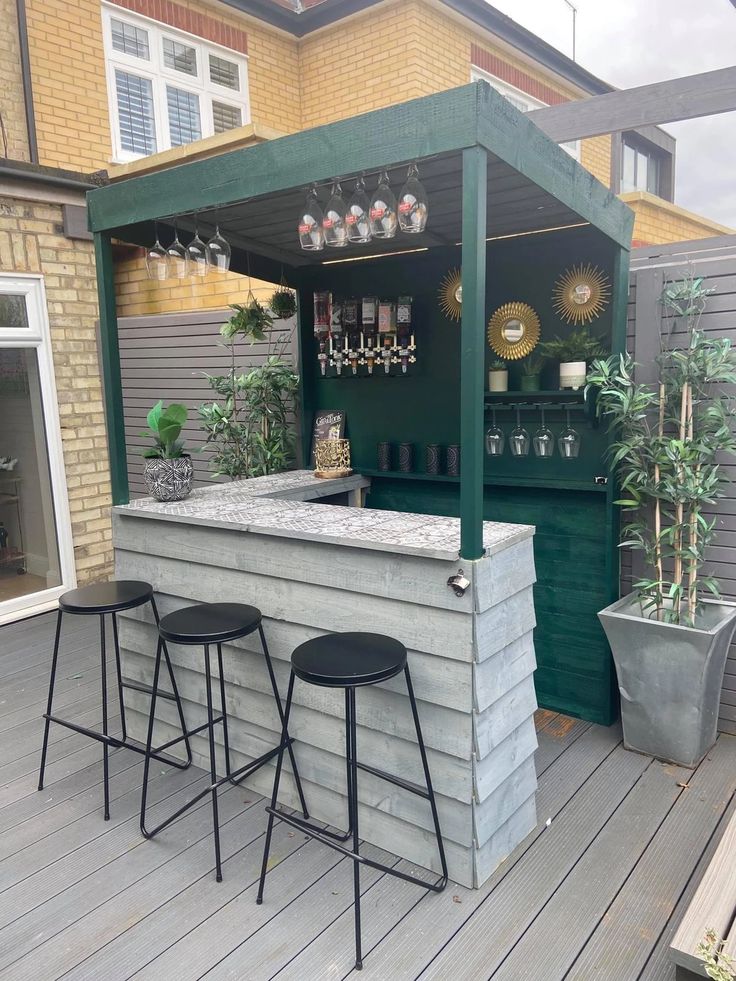 an outdoor bar with three stools on the deck