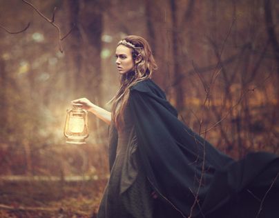 a woman holding a lantern in the woods