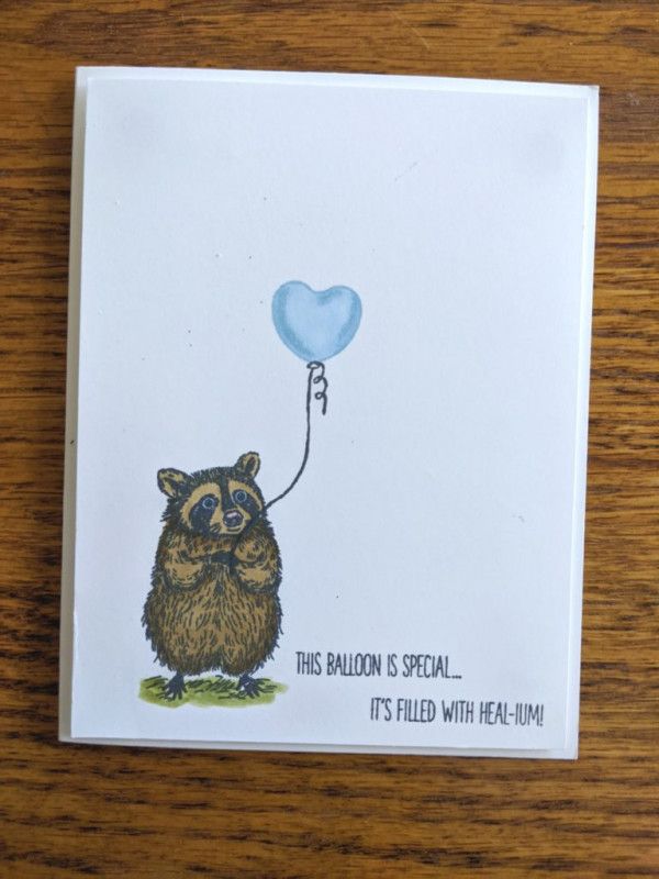 a card with a raccoon holding a heart shaped balloon on it's string