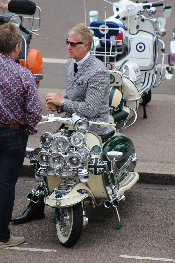 two men standing next to each other near motorcycles