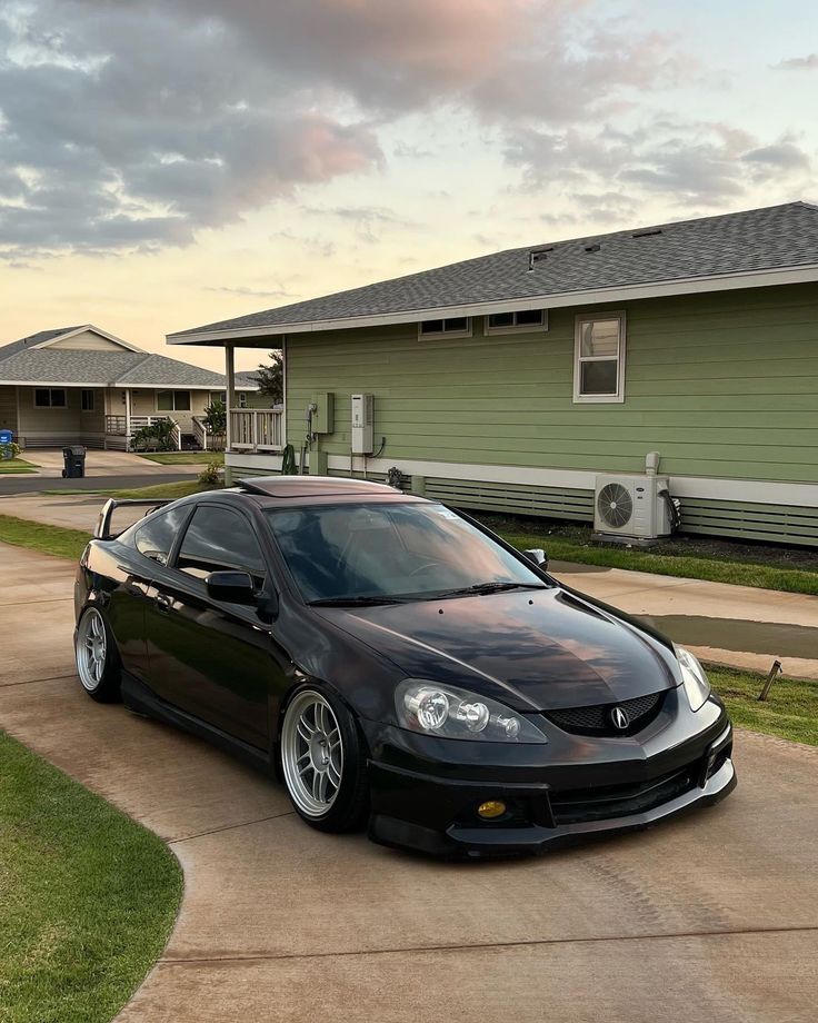 a black car parked in front of a green house