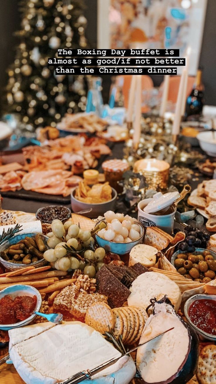 a table filled with lots of different types of food on top of it and a christmas tree in the background