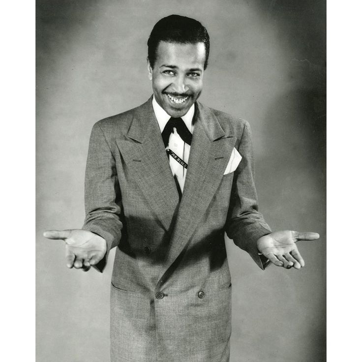 a black and white photo of a man in a suit with his hands out to the side