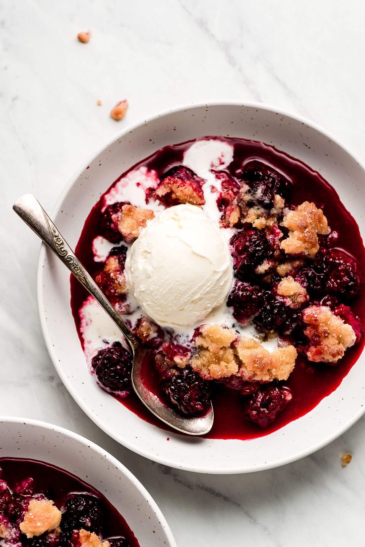 two bowls filled with fruit and ice cream on top of a white countertop next to each other