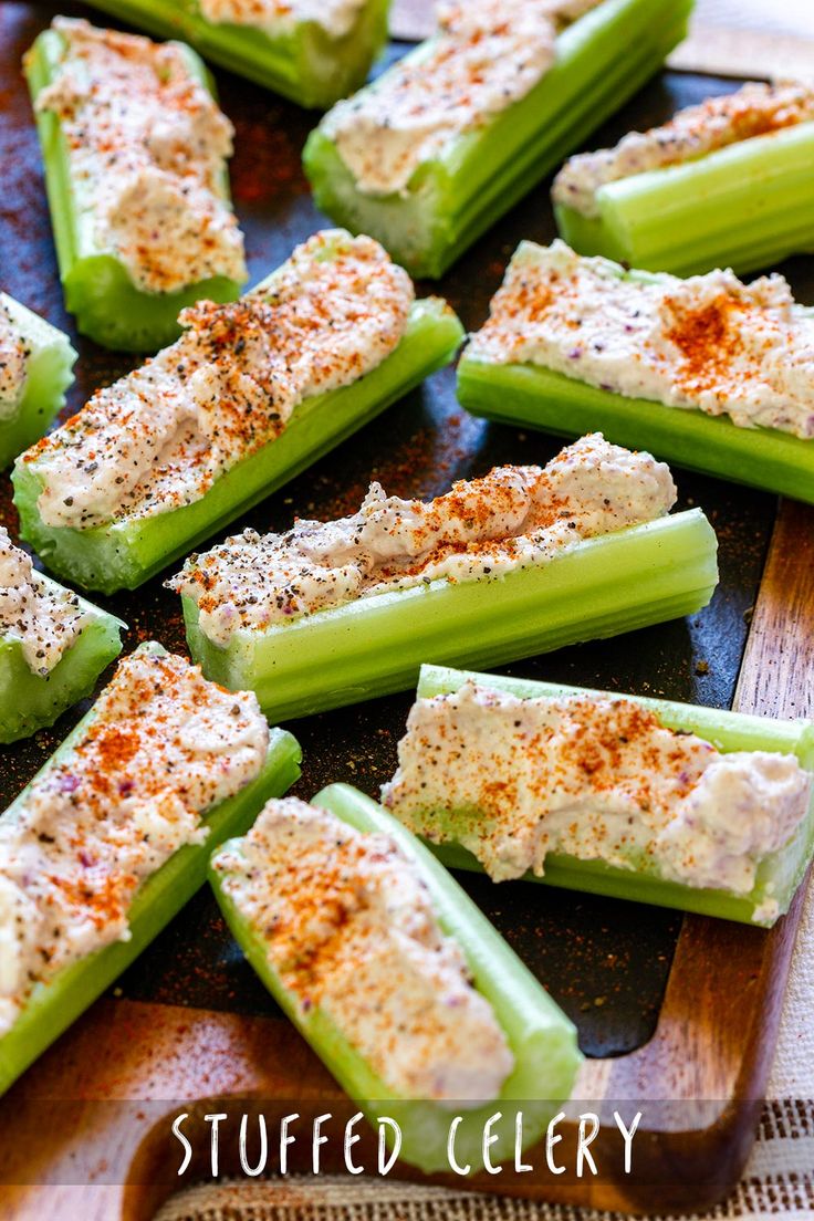 several celery sticks with cheese and seasoning on them sitting on a cutting board