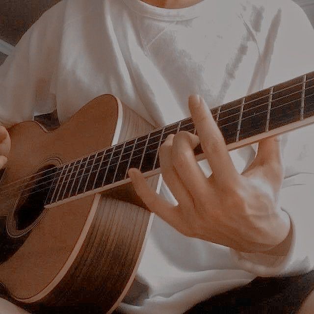 a man is playing an acoustic guitar while sitting down with his hands on the strings