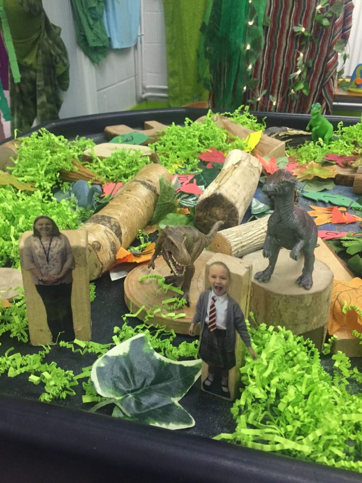 there is a small boy standing in front of fake trees and logs with animals on them