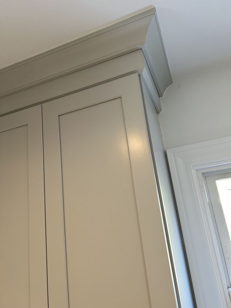 a kitchen with white cupboards and a window in the backround is shown