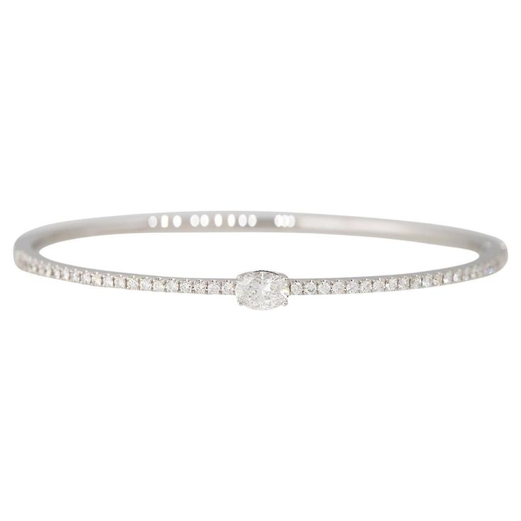 18k White Gold 1.15ctw Oval Cut Diamond Pave Bangle Bracelet Material: 18k White Gold Diamond Details: The center Oval Cut Diamond is approximately 0.55 carats. There are approximately 0.66 carats of round brilliant diamonds around the bangle as well. Diamond Clarity: All diamonds are approximately SI (Slightly Included) in clarity Diamond Color: All diamonds are approximately F/G/H in color Total Weight: 10.2g, 6.6dwt Size: The bracelet is approximately 6.25 inches in length and approximately 1.8mm x 2.8mm Additional Details: This item comes with a presentation box! SKU: G13820 This diamond bracelet is unique, with a larger, Oval-cut diamond in the center of the bracelet, weighing approximately 0.55 carats. This piece is also set with smaller round brilliant cut diamonds, that go halfway Luxury Oval Diamond Bangle, Luxury Oval Bracelets With Diamond Accents, Luxury Oval Diamond Cut Bracelet, Oval Diamond Bangle Fine Jewelry, Luxury White Oval Diamond Bracelet, Pave Bangle, Modern Bracelets, Oval Cut Diamond, Oval Cut