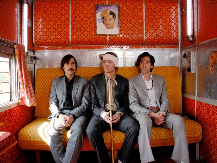 three men sitting on a bus with orange walls