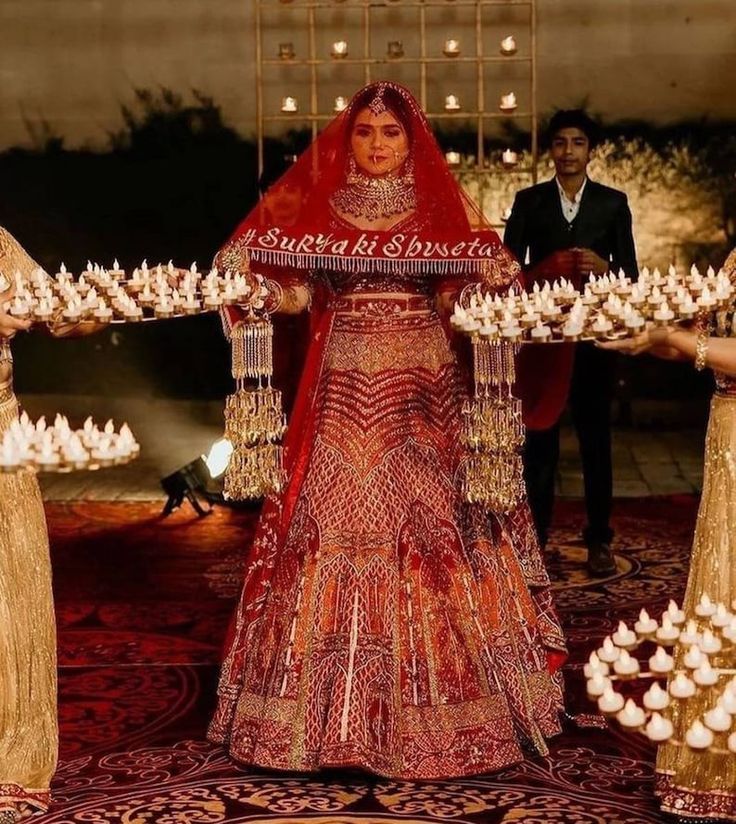 a woman in a red and gold wedding dress with two other people standing behind her