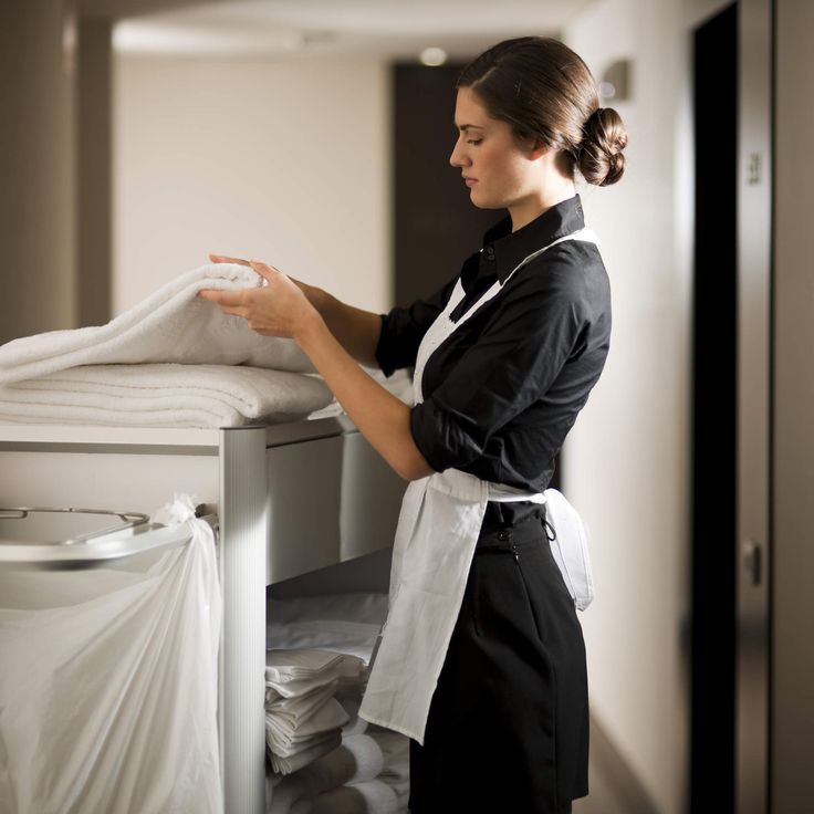 a woman standing in front of a stack of folded towels on top of a table