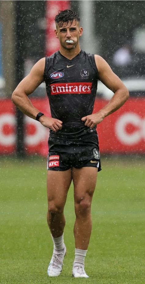 a rugby player standing in the rain with his hands on his hips and one hand on his hip