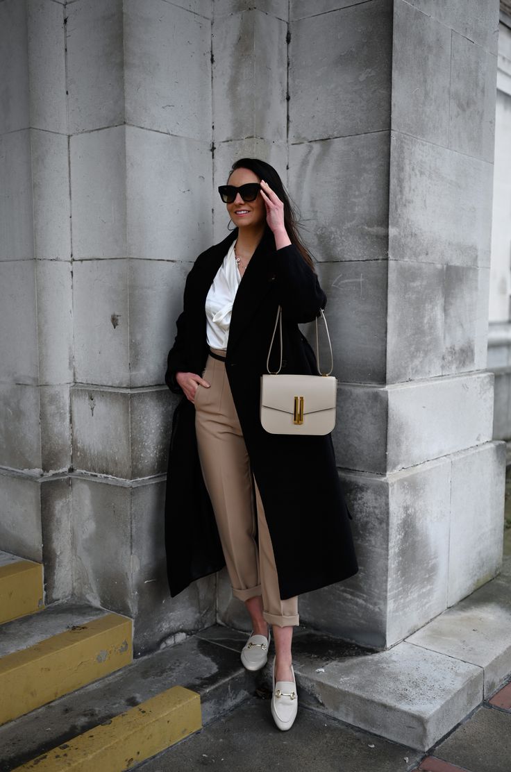 Wearing the Vancouver cross-body bag in a stunning taupe-coloured smooth leather from DeMellier London. Stone-coloured trousers complimented with a gold clasp black leather belt, on top a white silk bow tie blouse for added texture. Wrapped up in Other Stories belted wool coat in black. The look is completed with some neutral sophisticated leather loafers. #DeMellierLondon #DeMellierBag #Luxury #LuxuryHandbag #LuxuryCrossbodyBag #Taupe #TaupeBag #LuxuryStyling #ootd #designerbag White Bag Outfit Winter, Demellier Vancouver Bag, Taupe Purse Outfit, Demellier Vancouver Bag Outfit, Demellier Bags Outfit, Taupe Bag Outfit, Chloe Marcie Bag Outfit, Demellier Bags, Demellier London