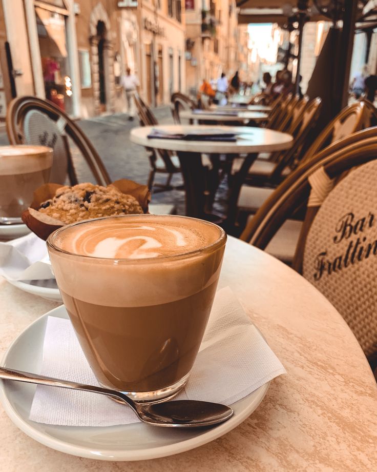 a cappuccino is sitting on a table in an outdoor cafe