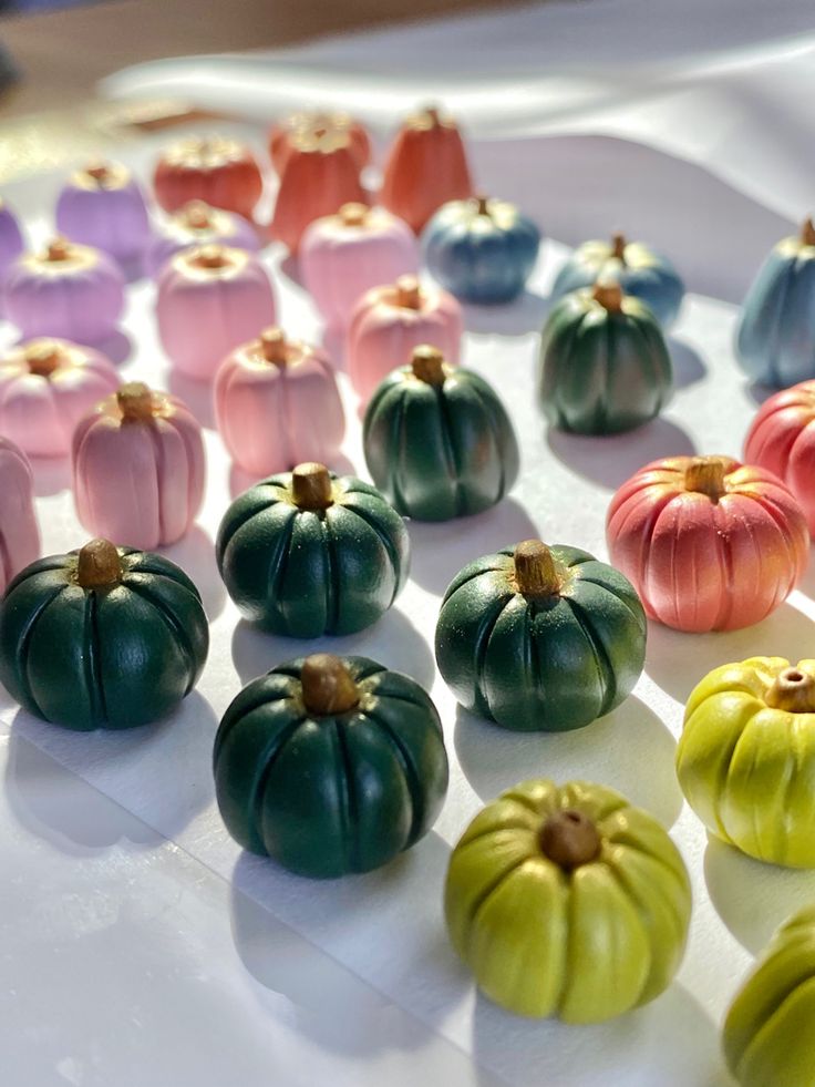 there are many small pumpkins sitting on the table and one is pink, green, blue, yellow