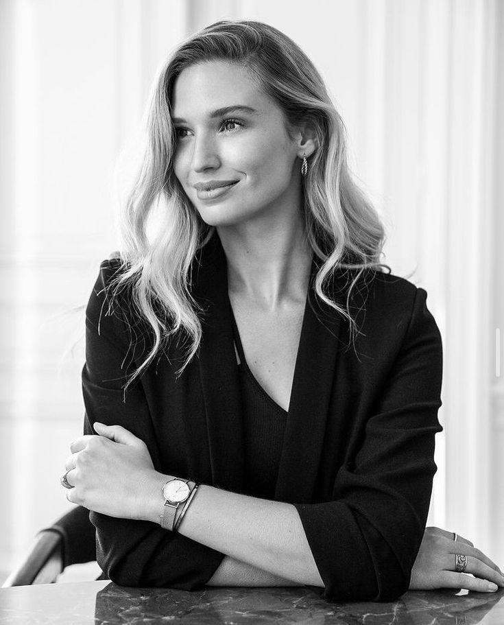 a black and white photo of a woman with her arms crossed sitting at a table