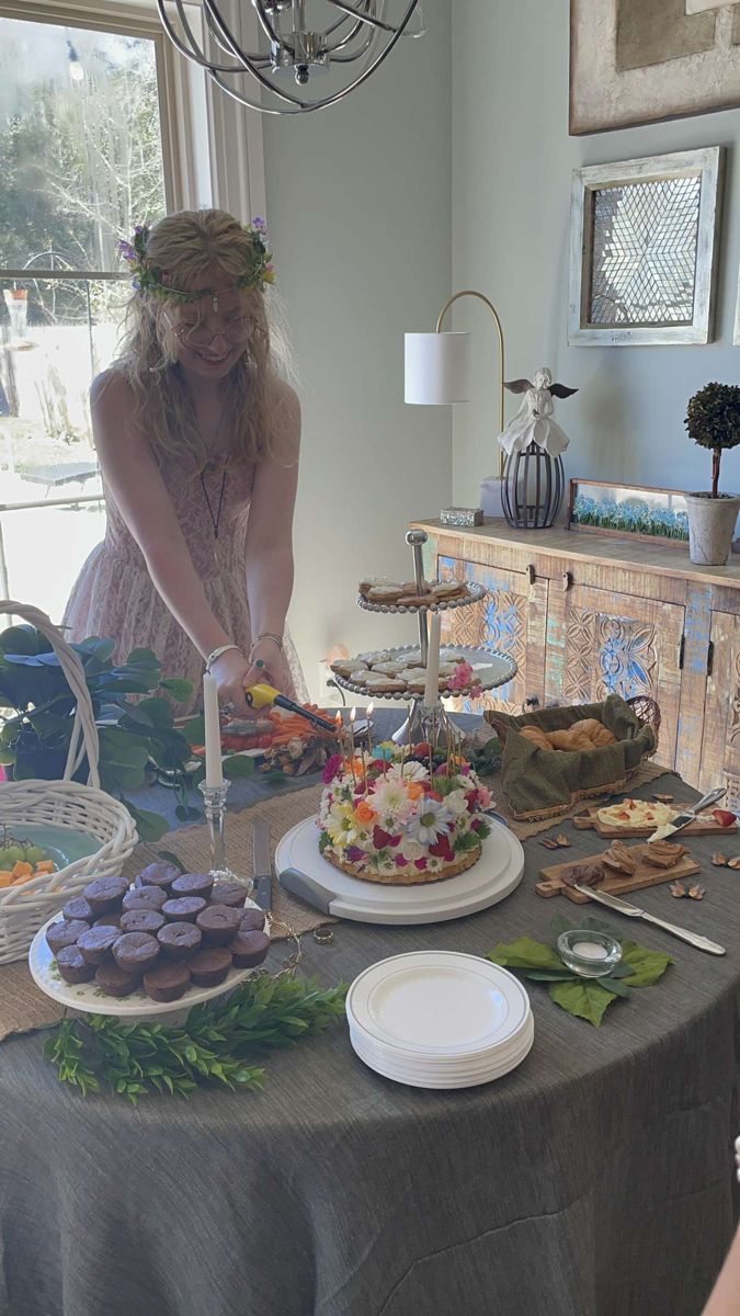 a woman standing in front of a table filled with cakes and desserts on it