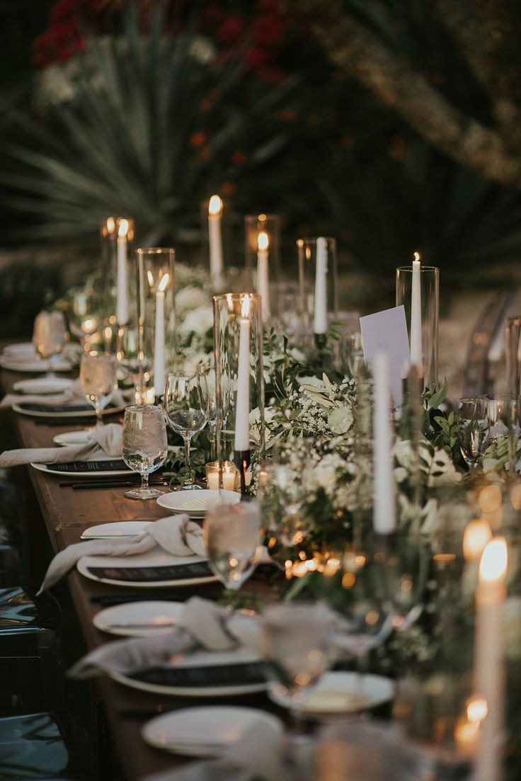 a long table is set with candles and place settings for dinner guests to sit at