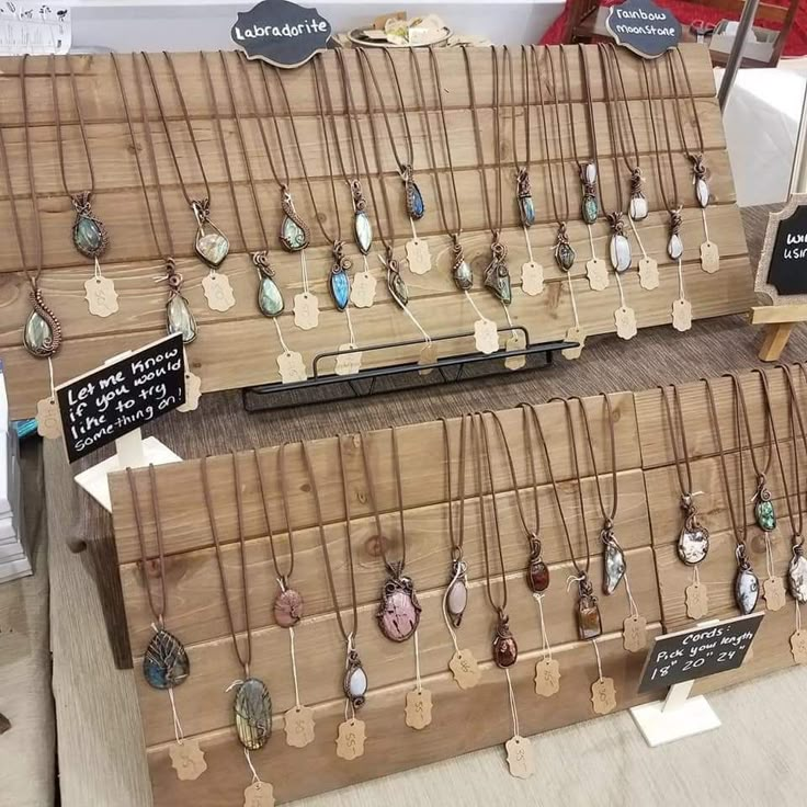 two wooden racks with necklaces on them and price tags attached to the hooks in front