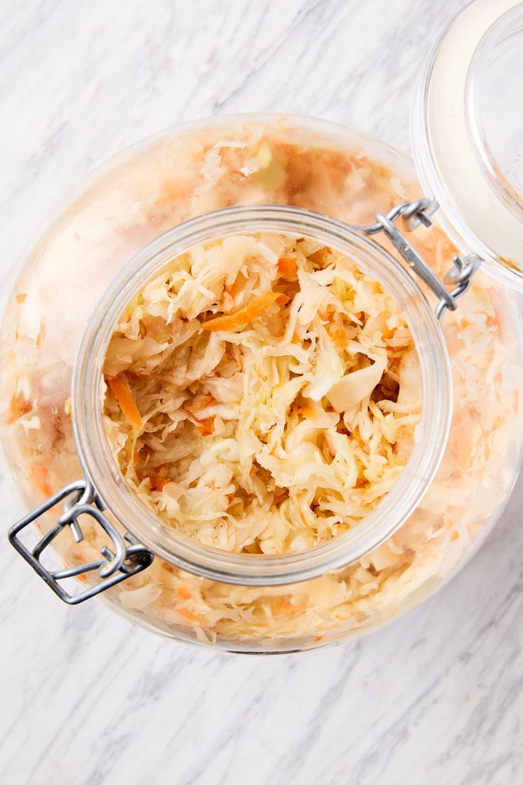 a glass jar filled with food sitting on top of a white marble counter next to a plastic container