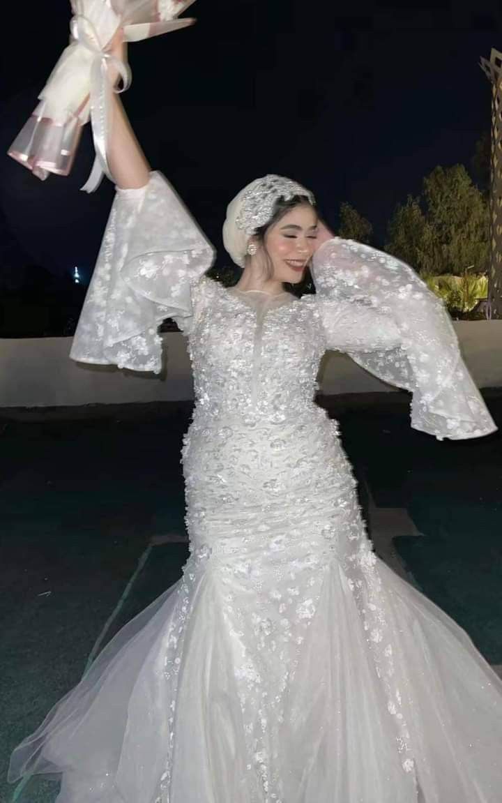 a woman in a white wedding dress holding her arms up