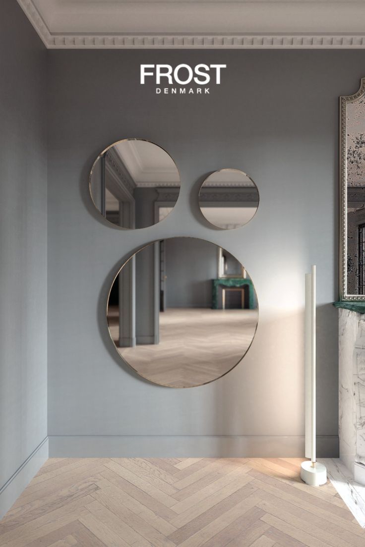 three circular mirrors on the wall above a fireplace in a room with parquet flooring