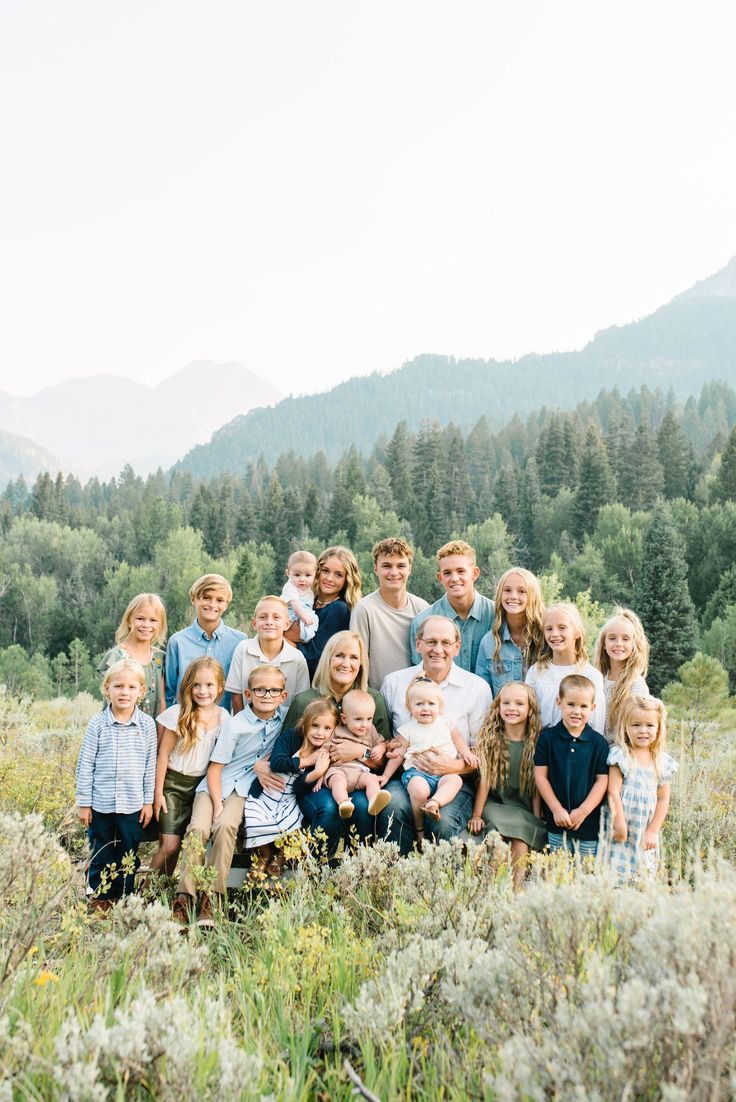 a large group of children and adults posing for a photo in front of some mountains